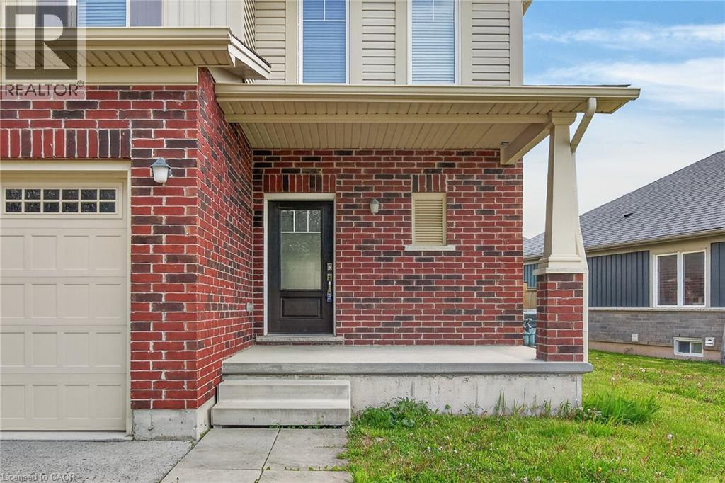 Red brick facade with a beige garage door and covered entry - 9 Winterberry Boulevard, Thorold, ON
