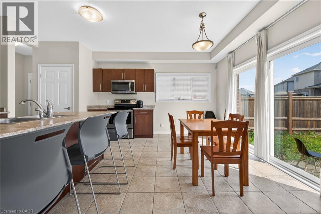 Kitchen featuring wood-finish cabinetry, stainless steel appliances, and a breakfast bar with a sink - 9 Winterberry Boulevard, Thorold, ON