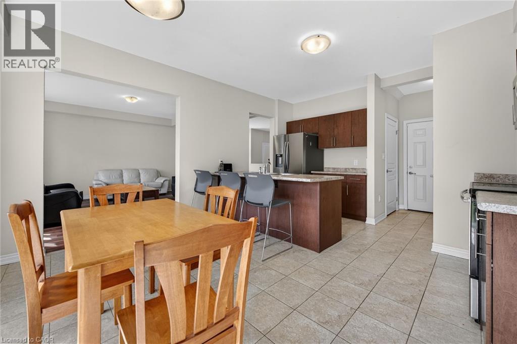 Kitchen with wood-finish cabinetry, stainless steel refrigerator, and granite-look countertops - 9 Winterberry Boulevard, Thorold, ON