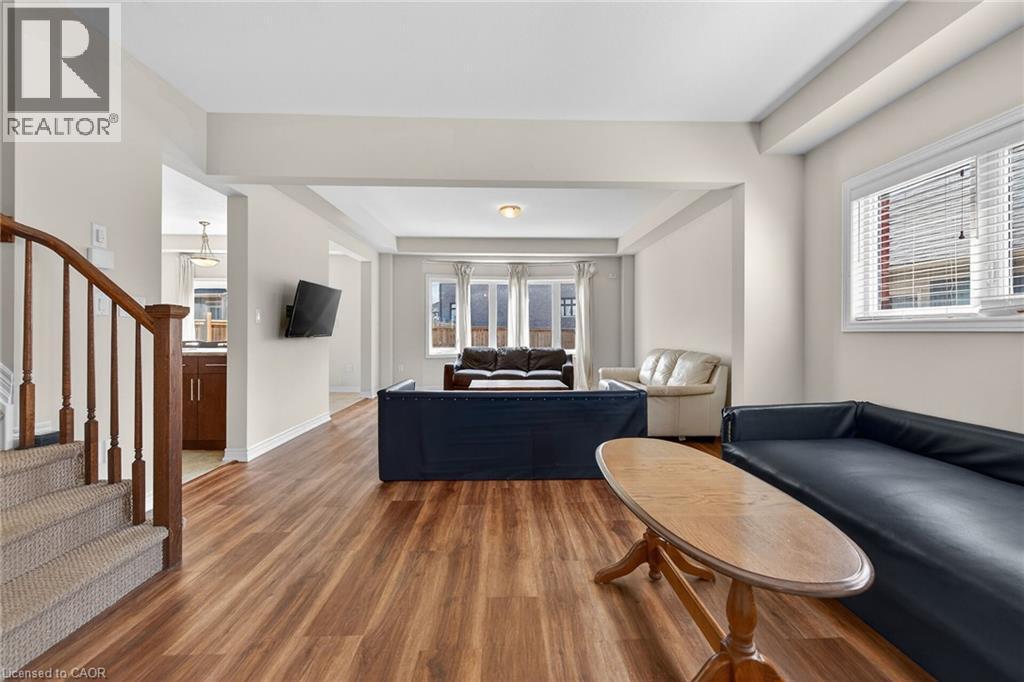 Wood-finish flooring throughout, curved wooden staircase with carpeted treads, and multiple windows providing natural light - 9 Winterberry Boulevard, Thorold, ON