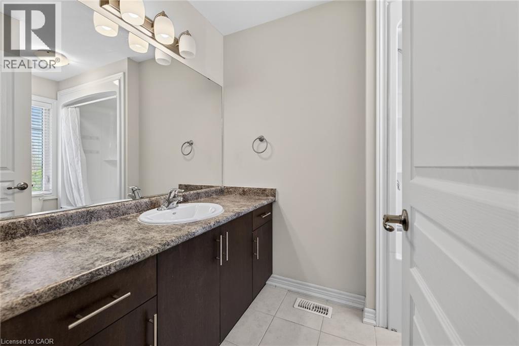 Bathroom featuring a single vanity with dark wood-finish cabinetry, a white oval sink, and a marbled countertop - 9 Winterberry Boulevard, Thorold, ON
