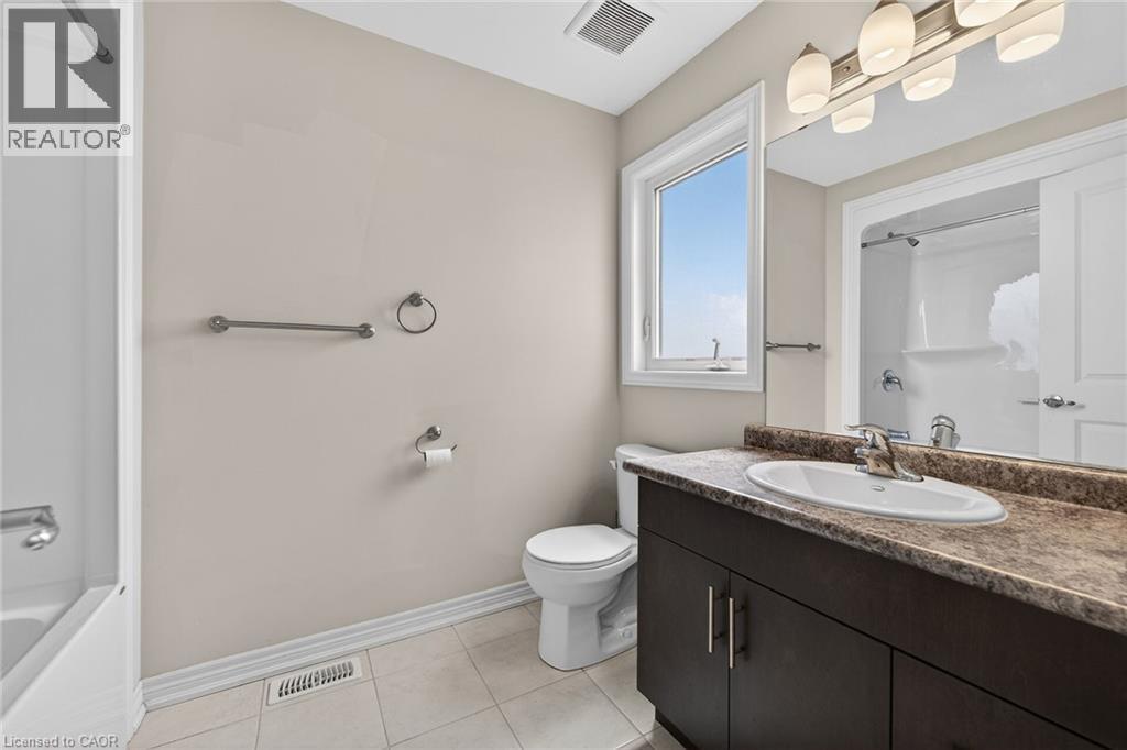 Bathroom featuring a white bathtub, a single vanity with a dark wood-finish cabinet, a light-toned countertop, a rectangular mirror, and a window - 9 Winterberry Boulevard, Thorold, ON