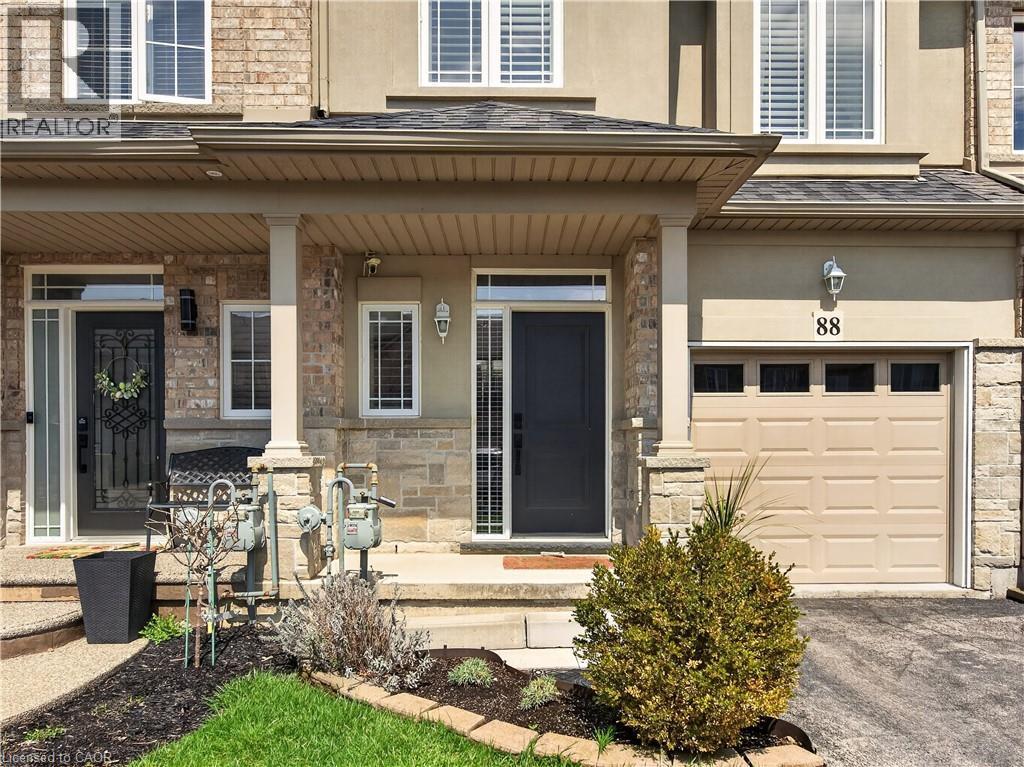 Brick and stone facade with a covered entry, single garage door, and decorative exterior lighting - 88 Highgate Drive, Hamilton, ON