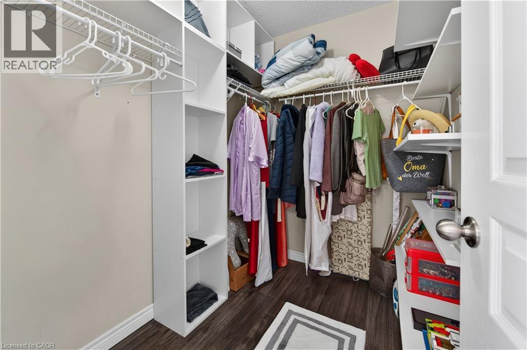 Walk-in closet featuring wire shelving, built-in organizers, hanging rods, wood-finish flooring, and a paneled door with a brushed nickel knob - 88 Highgate Drive, Hamilton, ON