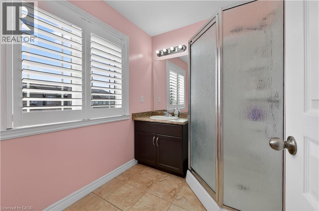 Bathroom featuring a dark wood-finish vanity with a surface-mounted sink, a glass-enclosed shower, and plantation shutters - 88 Highgate Drive, Hamilton, ON