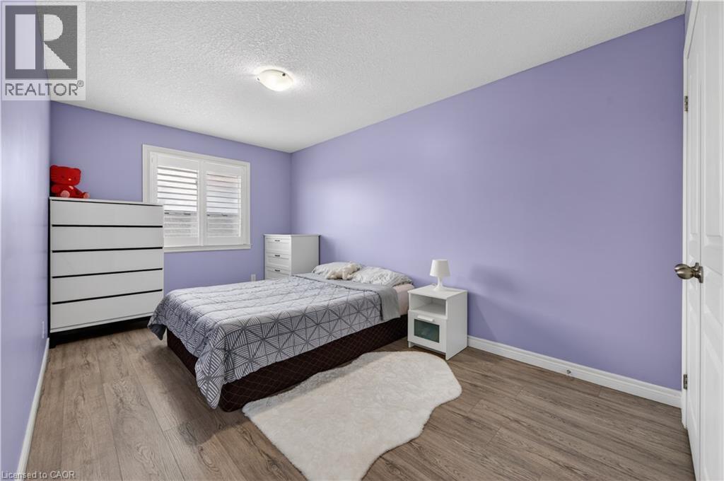 Wood-finish flooring, white plantation shutters, and a ceiling-mounted light fixture - 88 Highgate Drive, Hamilton, ON