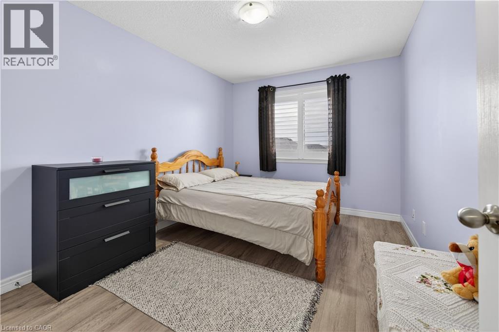 Wood-finish flooring with white baseboards and light purple wall color - 88 Highgate Drive, Hamilton, ON