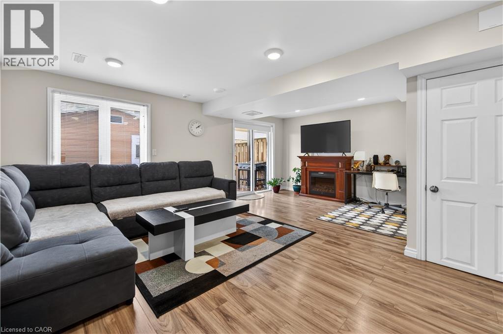 Recessed lighting, wood-finish flooring, white paneled door, sliding glass door, and a built-in electric fireplace with a wood mantel - 88 Highgate Drive, Hamilton, ON