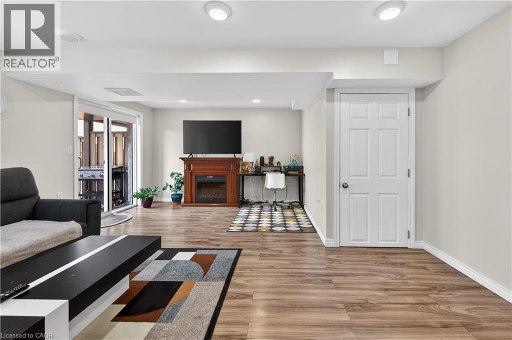 Recessed lighting, wood-finish flooring, white paneled door, sliding glass doors, built-in electric fireplace with wood surround - 88 Highgate Drive, Hamilton, ON