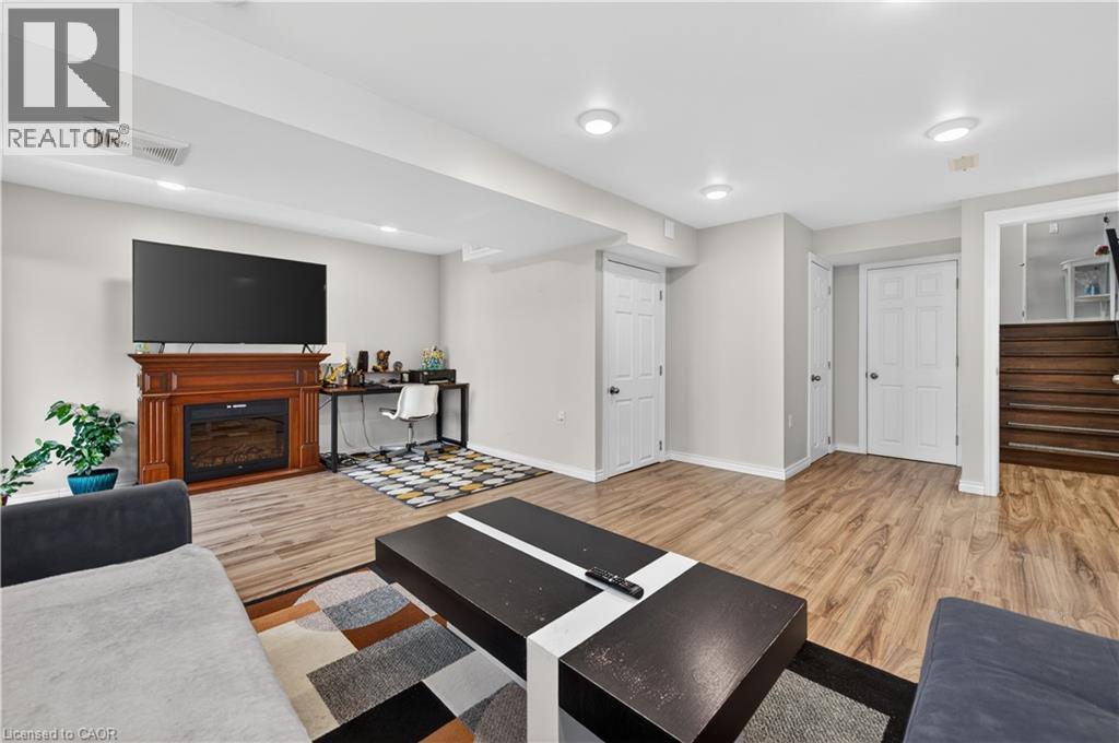 Recessed lighting, light wood-finish flooring, white panel doors, and a decorative fireplace with a wood-finish mantel - 88 Highgate Drive, Hamilton, ON