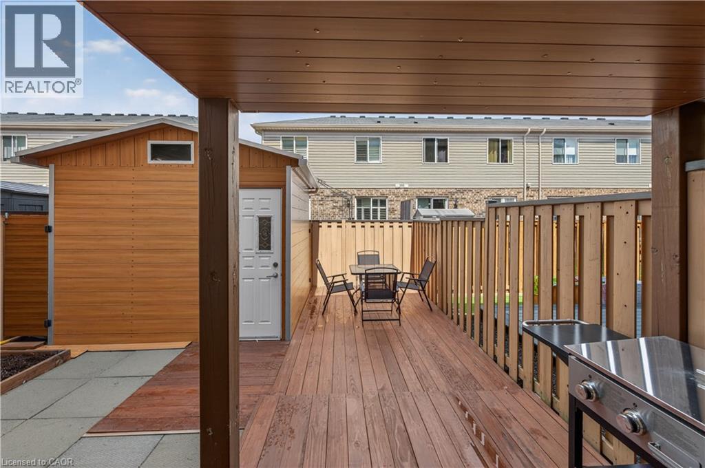 Expansive deck with wood-finish flooring, a covered patio area, and a private storage shed - 88 Highgate Drive, Hamilton, ON
