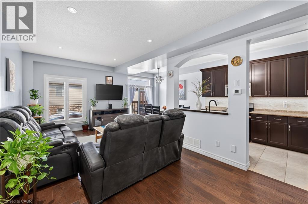 Hardwood-finish flooring, recessed lighting, and a kitchen with dark cabinetry, light countertops, and a tile backsplash - 88 Highgate Drive, Hamilton, ON