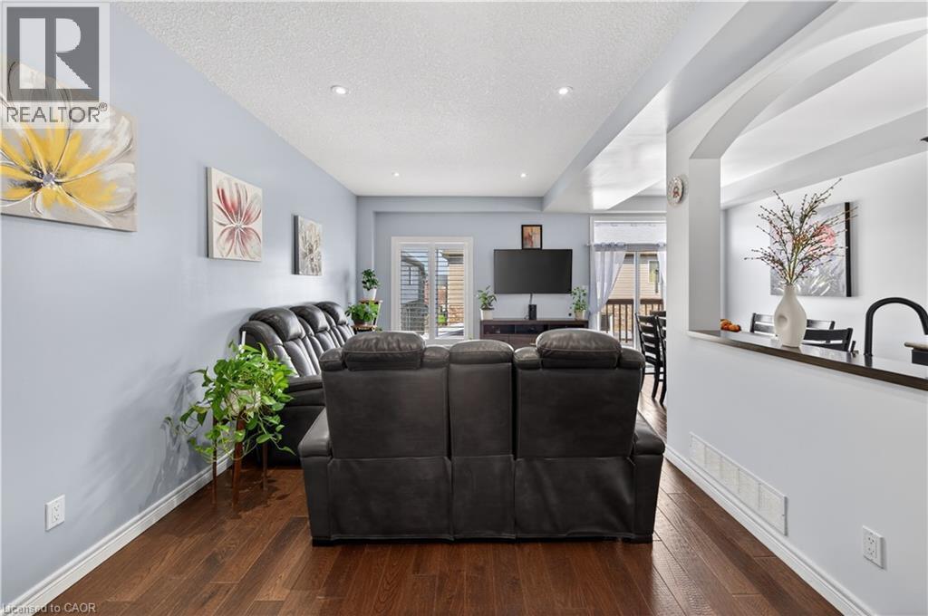Open-concept living area with wood-finish flooring, recessed lighting, and a sliding glass door - 88 Highgate Drive, Hamilton, ON