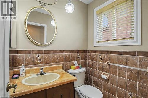 Bathroom featuring a vanity with an integrated sink, patterned brown wall tile, and a window with blinds - 14 Indian Crescent, Hamilton, ON 