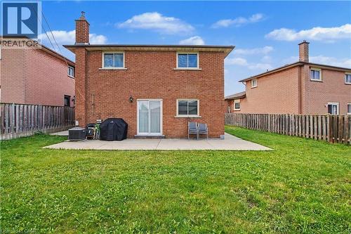 Red brick exterior featuring multiple windows with white trim, a concrete patio, and a sliding glass door - 14 Indian Crescent, Hamilton, ON 