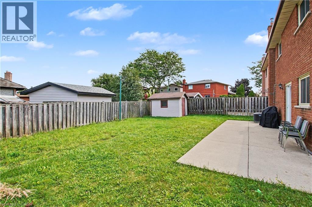 Expansive backyard featuring a lush lawn, privacy fencing, and a storage shed - 14 Indian Crescent, Hamilton, ON