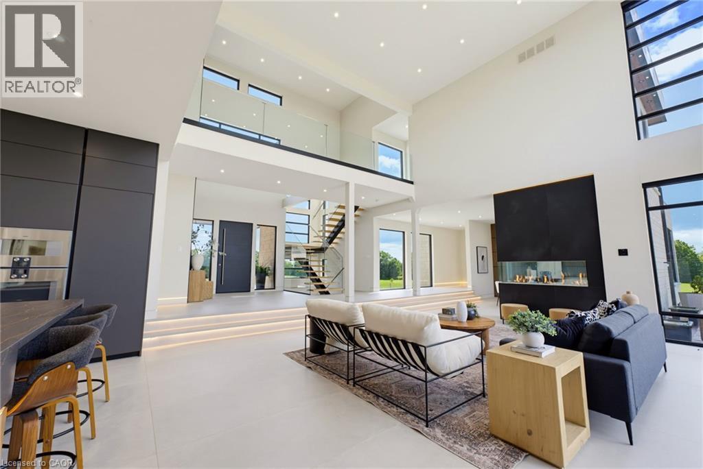 Modern open-concept living space featuring soaring ceilings with skylights, polished concrete flooring throughout, and abundant natural light from multiple windows and glass doors - 5709 Forth Line, Hillsburg, ON