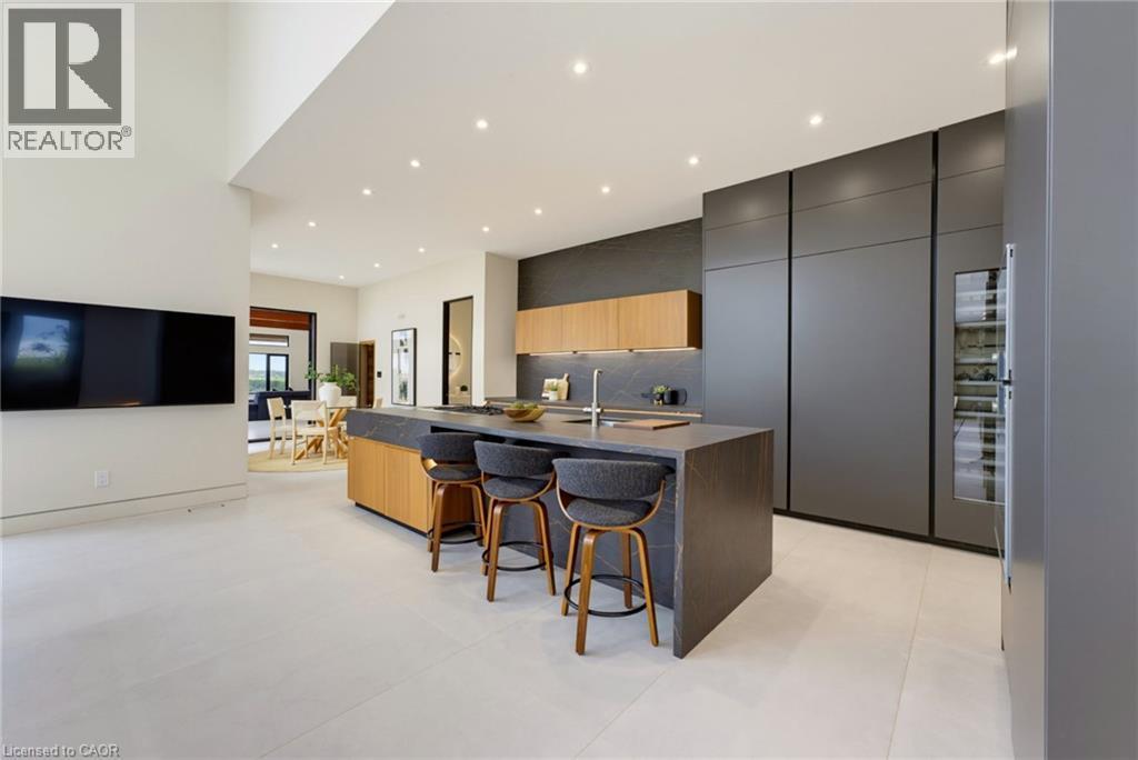 Contemporary open-concept kitchen and living area featuring a large waterfall-edge island with seating for multiple guests, custom cabinetry in charcoal and natural wood tones, stainless steel applian - 5709 Forth Line, Hillsburg, ON