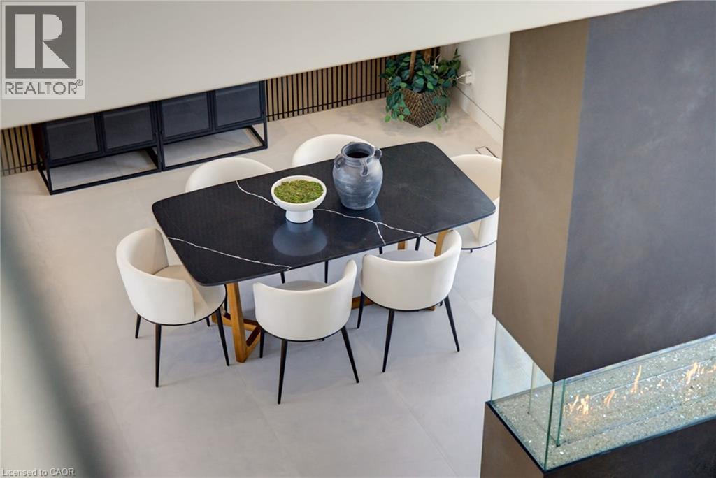 Modern dining area featuring a black wood-finish table with geometric base, four cream upholstered chairs with metal legs, light wood-finish flooring, and a bright, open layout accented by a built-in - 5709 Forth Line, Hillsburg, ON