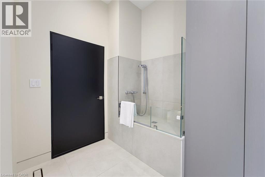Contemporary bathroom featuring a bathtub with a partial glass enclosure, tile surround, and a handheld shower fixture - 5709 Forth Line, Hillsburg, ON