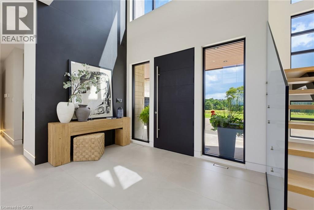 Modern foyer showcasing a dramatic deep navy accent wall, light-filled spaces with floor-to-ceiling windows, polished concrete flooring, and direct access to an expansive outdoor terrace - 5709 Forth Line, Hillsburg, ON