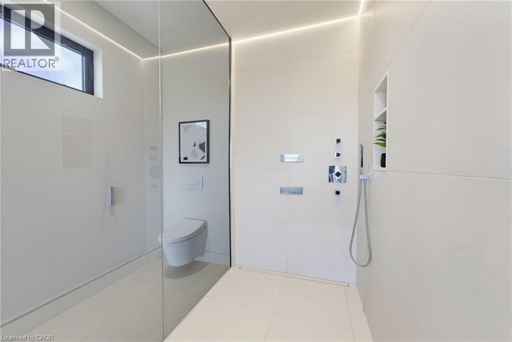 Sleek shower with a frameless glass enclosure, tiled walls, and a linear drain - 5709 Forth Line, Hillsburg, ON