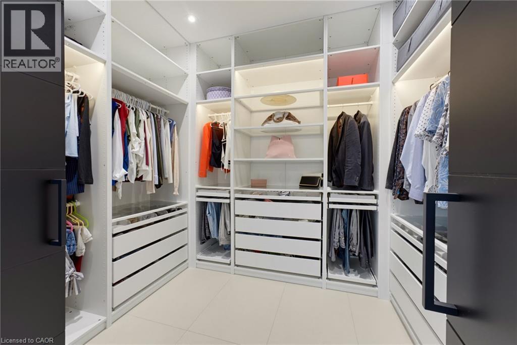 Walk-in closet featuring custom white cabinetry with multiple shelving sections, integrated drawers with horizontal pulls, and hanging rods for organized storage - 5709 Forth Line, Hillsburg, ON