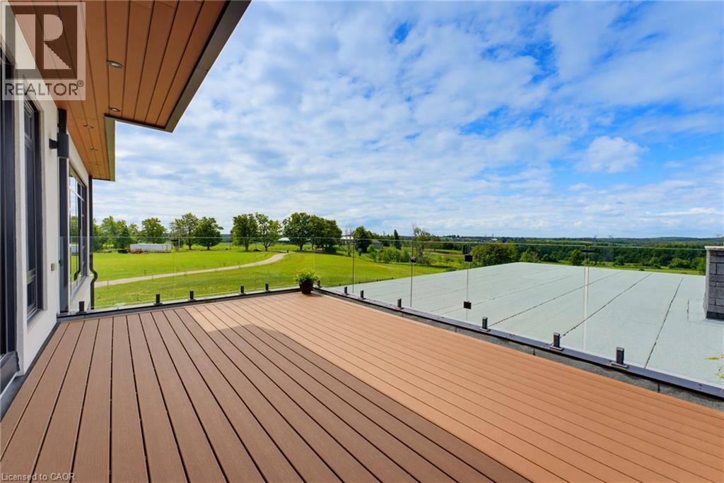 Expansive outdoor deck featuring composite decking, glass railing, and attached exterior lighting - 5709 Forth Line, Hillsburg, ON