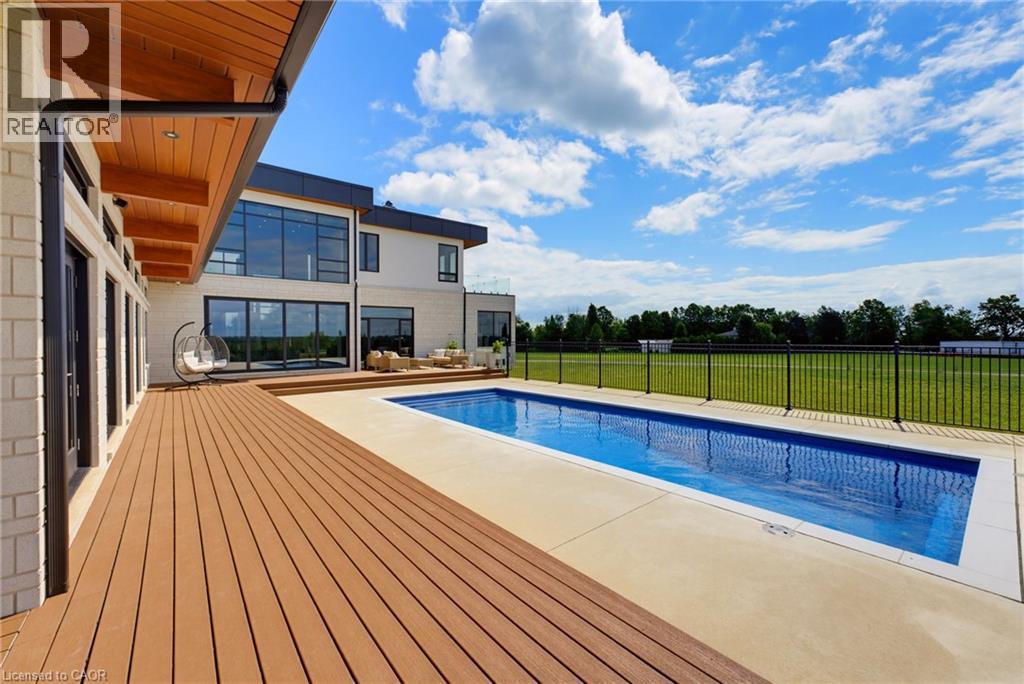 Expansive wood-finish deck, rectangular swimming pool, concrete pool surround, and a fenced perimeter - 5709 Forth Line, Hillsburg, ON