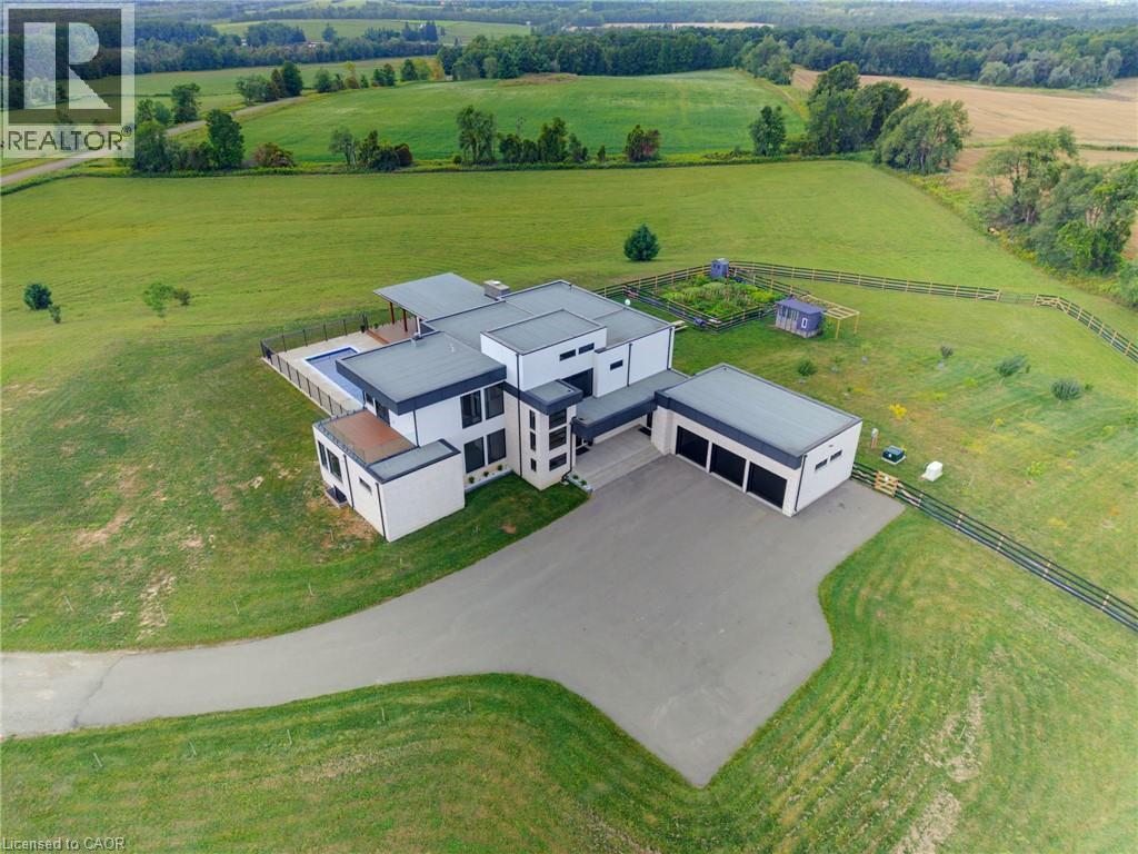 Contemporary architectural design with a flat roofline, an integrated swimming pool, an expansive driveway, a detached multi-bay garage, and surrounding green space - 5709 Forth Line, Hillsburg, ON