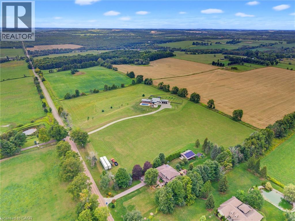Sprawling rural landscape featuring vast agricultural fields, established tree lines, and multiple residential properties - 5709 Forth Line, Hillsburg, ON