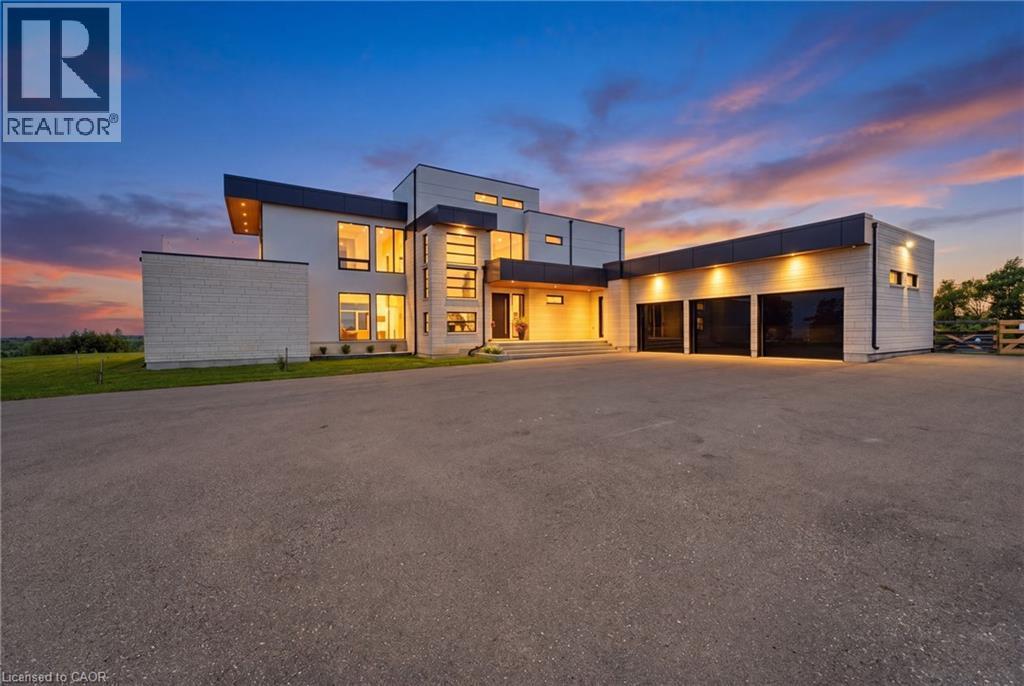Modern architectural exterior with expansive glazing, a multi-car garage, and a large paved driveway - 5709 Forth Line, Hillsburg, ON