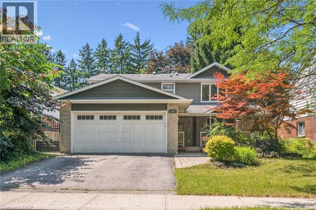 Welcoming two-story home featuring a spacious two-car garage with paneled doors, brick and siding exterior, and mature landscaping with Japanese maple accent trees - 345 Beechlawn Drive, Waterloo, ON