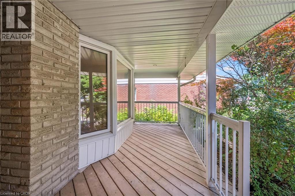 Covered wraparound porch featuring composite decking, white vinyl railings, and a corrugated metal ceiling - 345 Beechlawn Drive, Waterloo, ON