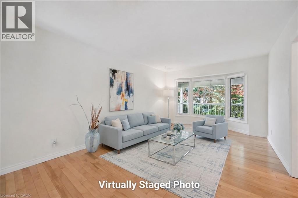 Bright, light-filled living room showcasing hardwood flooring, expansive glass doors and windows with natural outdoor views, neutral wall finishes, and an open floor plan ideal for entertaining - 345 Beechlawn Drive, Waterloo, ON