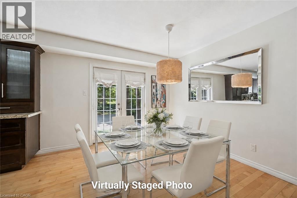 Dining area featuring wood-finish flooring, a contemporary pendant light fixture, and double glass-paneled doors - 345 Beechlawn Drive, Waterloo, ON