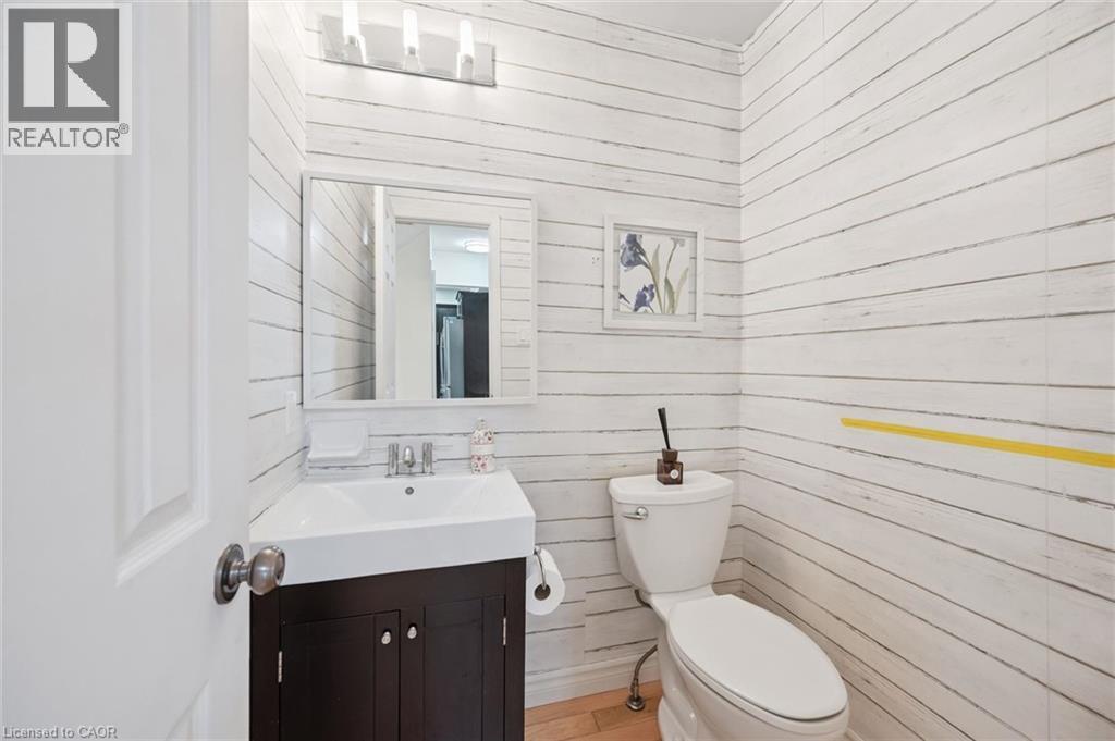 Powder room featuring shiplap-style walls, a white vanity with dark wood-finish cabinetry, a rectangular basin, and a modern three-light fixture - 345 Beechlawn Drive, Waterloo, ON