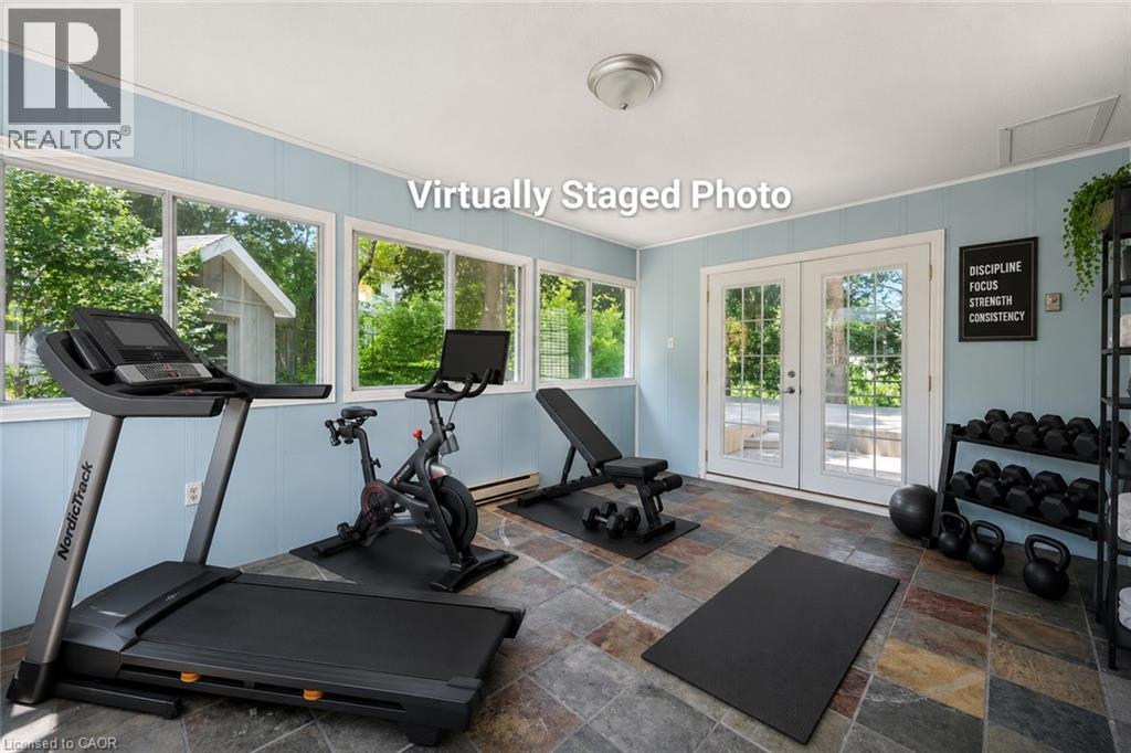 Flexible bonus room with slate tile flooring, light blue paneling, multiple windows, and French doors - 345 Beechlawn Drive, Waterloo, ON