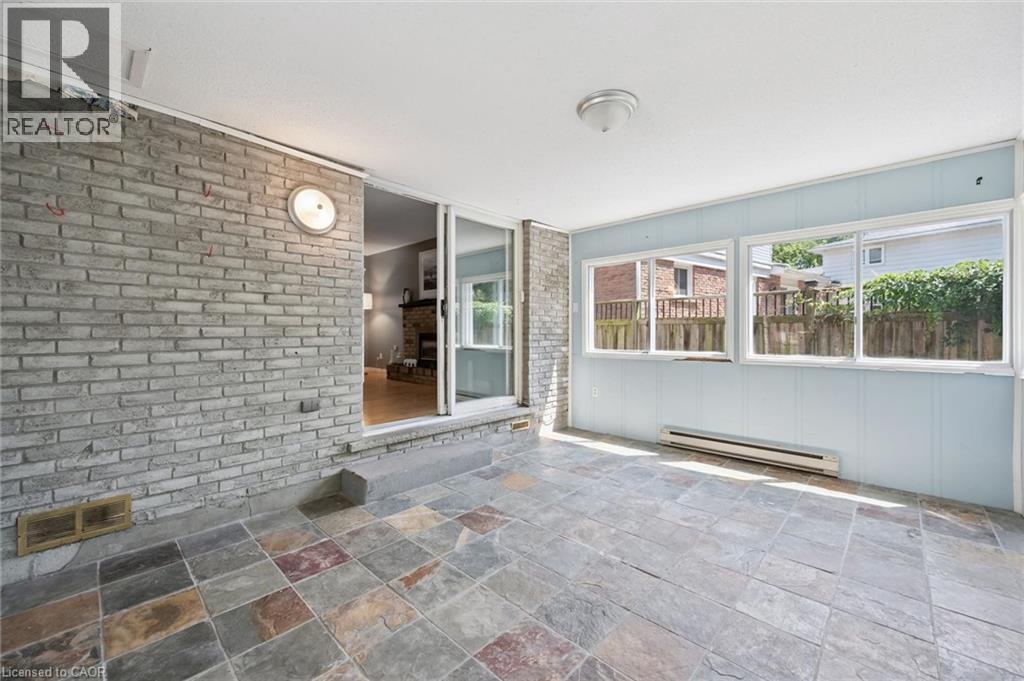 Sunlit covered patio with slate-finish tile flooring and expansive glass sliding doors opening to the residence - 345 Beechlawn Drive, Waterloo, ON