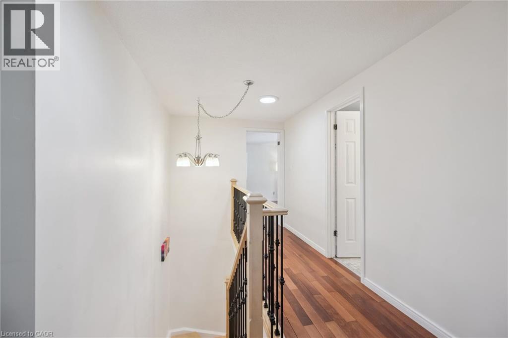 Upper-level hallway featuring wood-finish flooring, white walls, and a recessed ceiling light - 345 Beechlawn Drive, Waterloo, ON