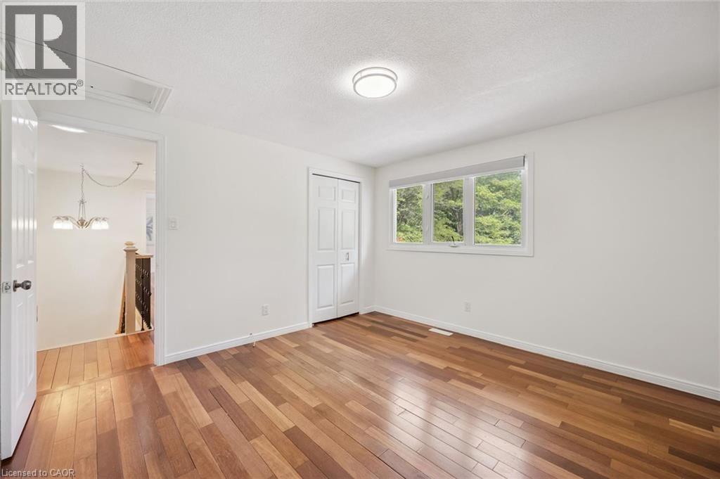 Spacious room featuring wood-finish flooring, white walls, and a three-pane window with natural light - 345 Beechlawn Drive, Waterloo, ON