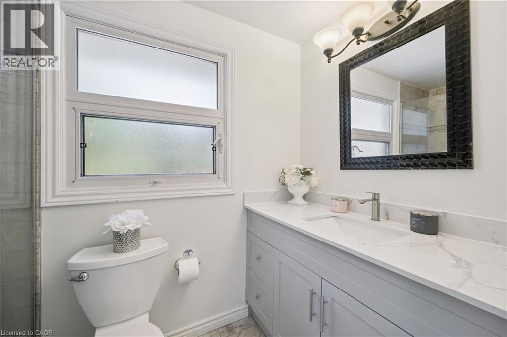 Bathroom featuring a single vanity with a solid surface countertop, an integrated sink, and brushed nickel fixtures - 345 Beechlawn Drive, Waterloo, ON