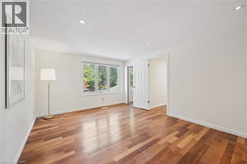 Spacious room featuring wood-finish flooring, recessed lighting, and a large multi-pane window - 345 Beechlawn Drive, Waterloo, ON