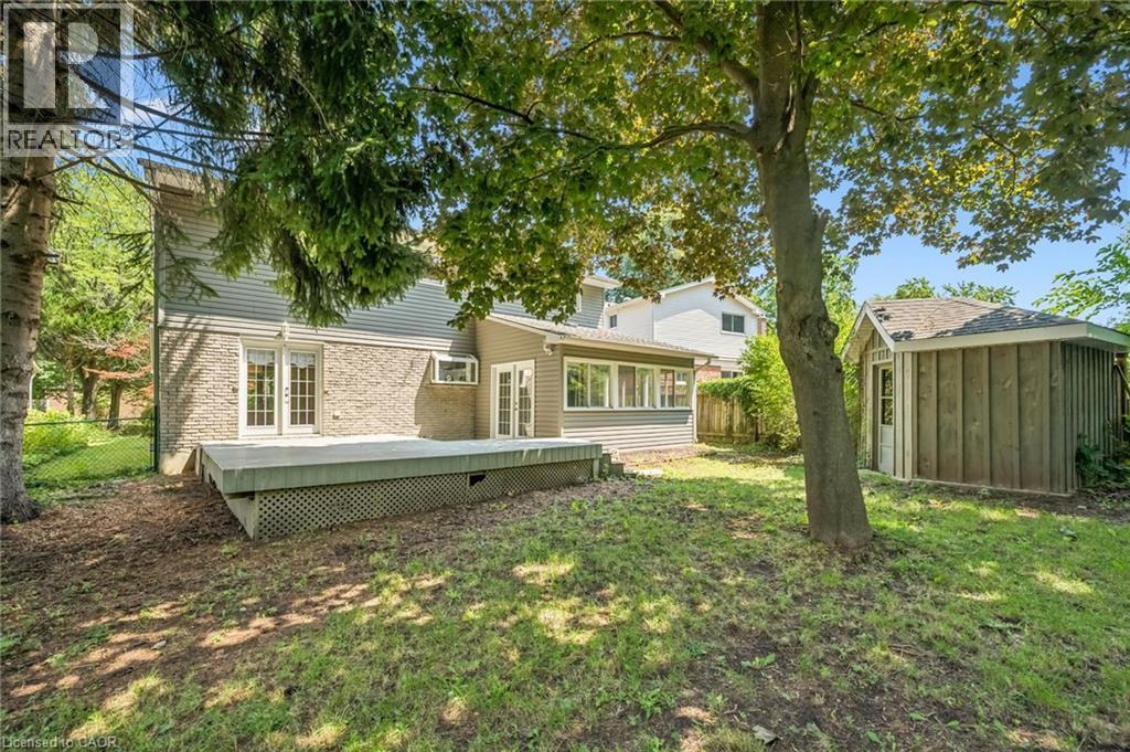 Spacious backyard retreat featuring mature shade trees, level lawn, and a single-story addition with large windows and a composite deck - 345 Beechlawn Drive, Waterloo, ON