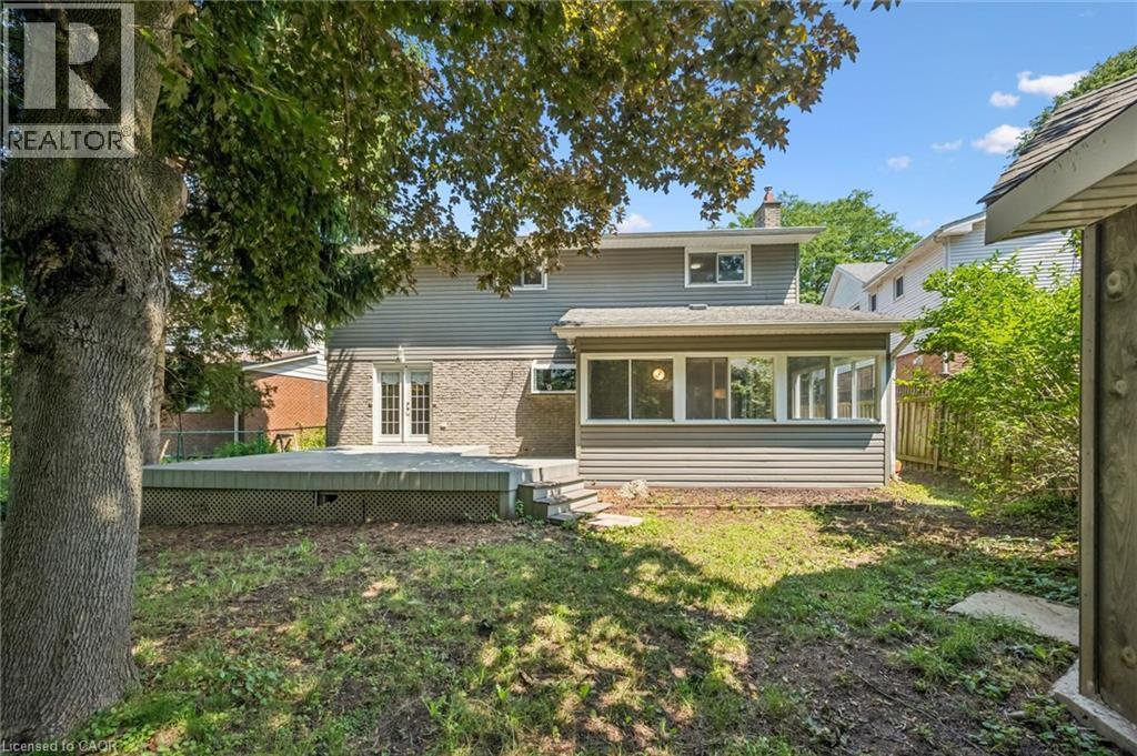 Rear exterior featuring a sunroom, a multi-level deck, and double French doors - 345 Beechlawn Drive, Waterloo, ON