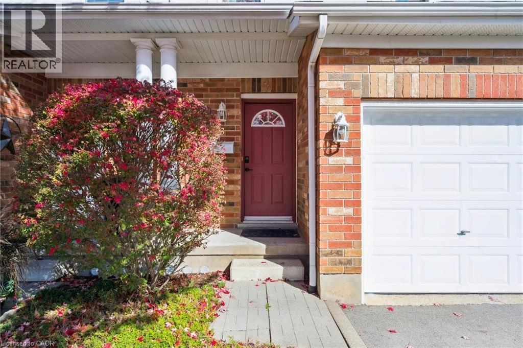 Brick exterior with a prominent red entry door featuring an arched window - 151 Clairfields Drive Unit# 3, Guelph, ON