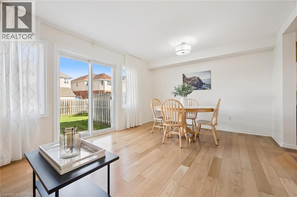 Expansive wood-finish flooring throughout, bright white walls, and a contemporary ceiling light fixture - 151 Clairfields Drive Unit# 3, Guelph, ON