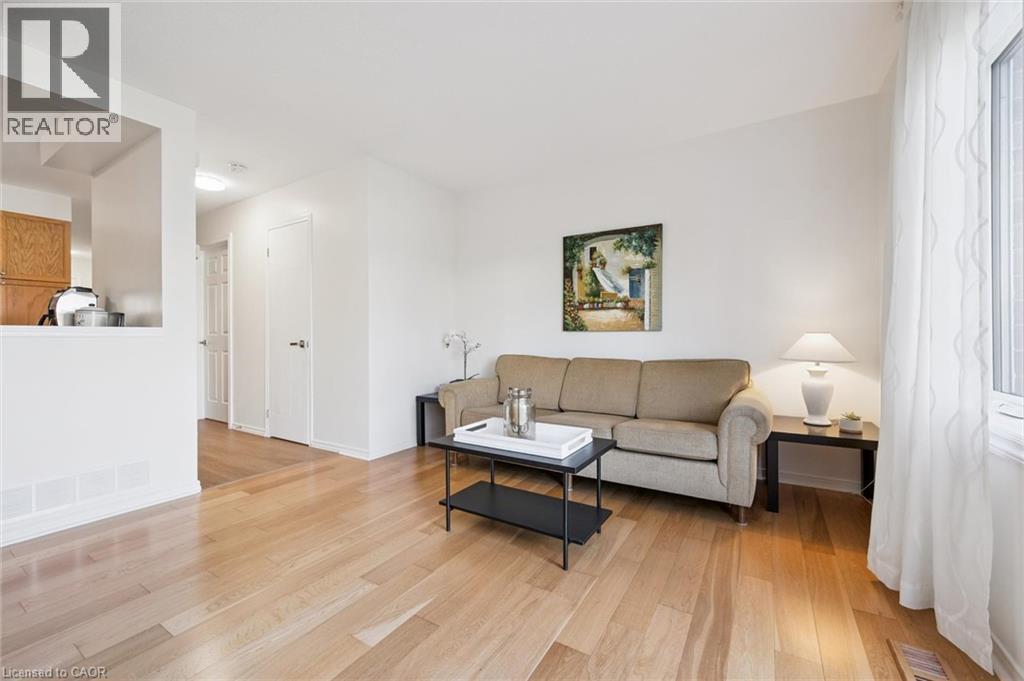 Light wood-finish flooring, white walls, and a pass-through window with wood cabinetry - 151 Clairfields Drive Unit# 3, Guelph, ON