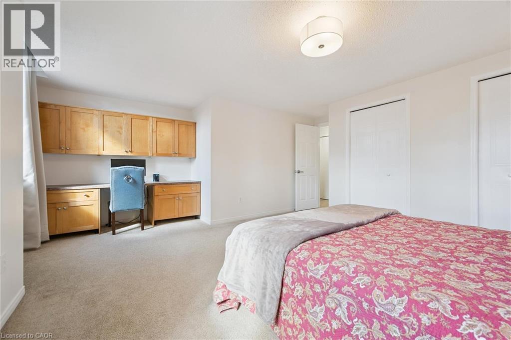 Built-in desk with wood-finish cabinetry, two wardrobe closets, and a semi-flush mount ceiling light - 151 Clairfields Drive Unit# 3, Guelph, ON