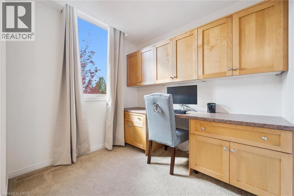 Built-in desk with wood-finish cabinetry, upper storage, and a textured countertop - 151 Clairfields Drive Unit# 3, Guelph, ON